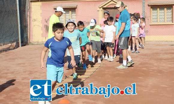 Bajo la supervisión de los instructores, los niños dan sus primeros golpes a la pequeña bola amarilla.