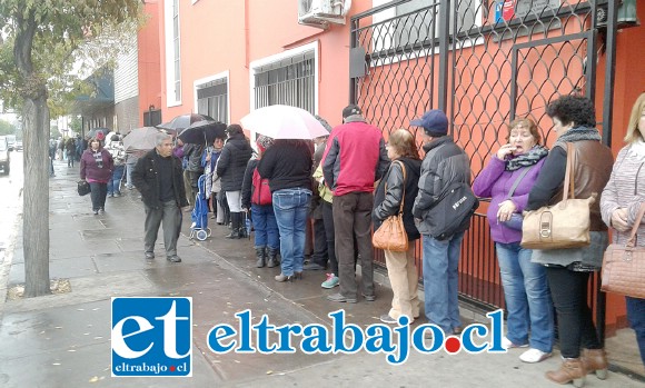 Adultos mayores mujeres y hombres con paraguas para guarecerse de la lluvia además del intenso frío.