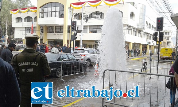 Carabineros en el lugar mientras numerosas personas observan la gran columna de agua brotar con fuerza desde el suelo.