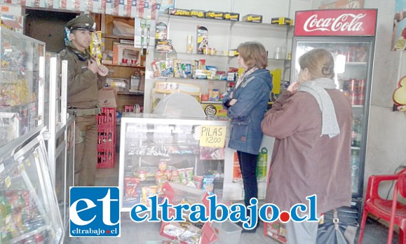 La afectada Sandra Rodríguez conversa con el carabinero al interior del negocio.