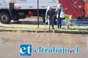 Una pareja de adultos mayores apoyándose en su bastón para poder cruzar debido al verdadero río que había en avenida Miraflores.