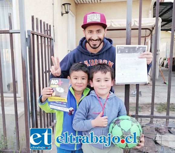 Un adulto con dos niños orgullosos y sonriendo muestran el formulario que los acredita como socio cooperador de bomberos.