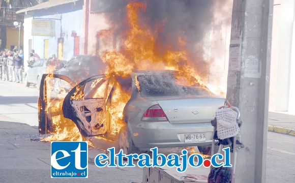 El momento exacto en que los delincuentes huyeron con el millonario botín, incendiando este vehículo en el frontis de la sucursal Servi Estado en calle Santo Domingo de San Felipe.