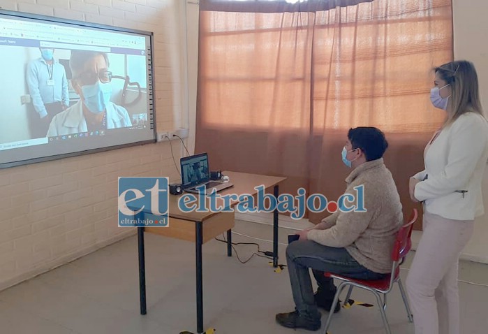 El médico cardiólogo Dr. Luis Foncea en plena consulta médica a distancia con un paciente, mientras es observado por la directora del SSA, Susan Porras.