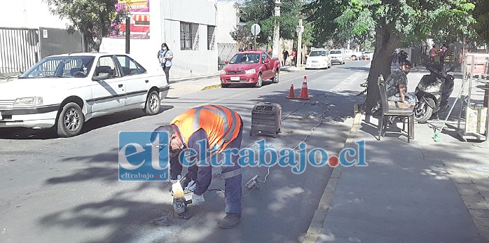 Un funcionario con un esmeril eléctrico corta los pernos que unían las tachas al cemento en calle Merced.