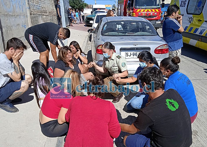EN ORACIÓN.- En un acto de solidaridad y humanidad, esta oficial de Carabineros y los vecinos del sector se unieron en oración para rogar a Dios no se llevara al pequeño niño.